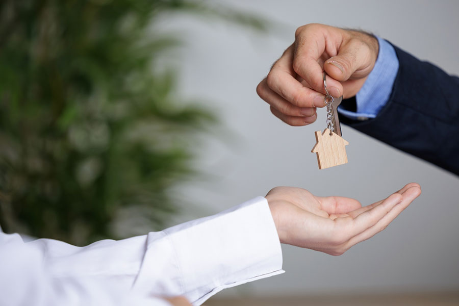 Notaire en train de donner les clés d'une maison ou d'un appartement à sa nouvelle propriétaires après avoir signé l'acte de vente dans son office notarial