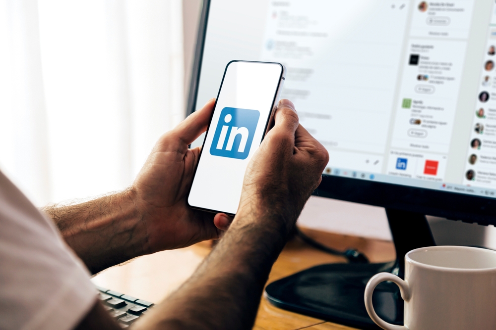 personne en train de consulter son profil Linkedin sur son smartphone et son pc