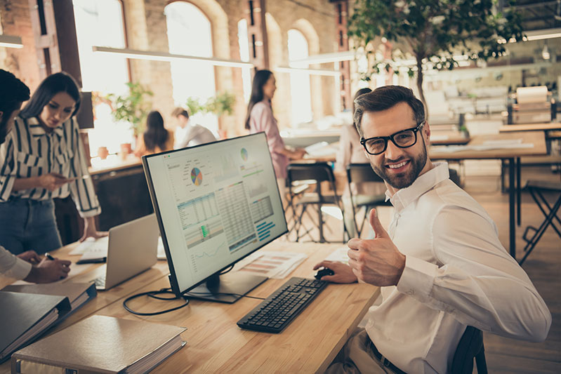 Homme content et levant son pouce devant son ordinateur